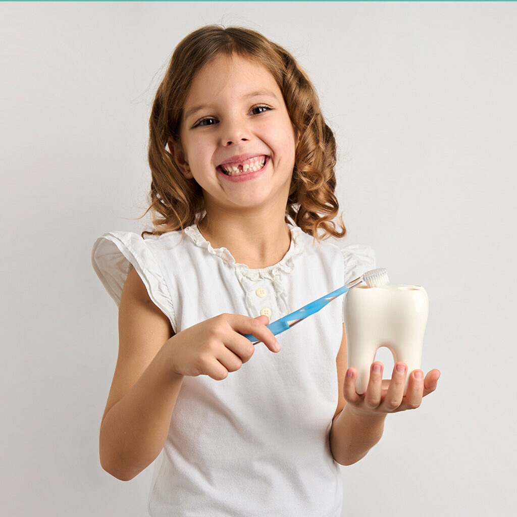 cute little girl with missing tooth brushing giant tooth